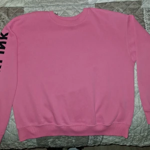 Rosa sweatshirt från H&M x Blackpink - Säljer en rosa sweatshirt från H&M i samarbete med Blackpink. Tröjan har ett tryck av en krona och texten 'BLACKPINK' på ryggen samt text på ärmen. Perfekt för fans av bandet!