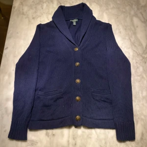 Ralph Lauren cardigan mörkblå storlek M - Skick: 8/10. Står storlek M men skulle säga att den lutar mer mot en S. Tröjan är från Lauren Ralph Lauren och har inga defekter. Om du är osäker på om den kommer passa kan du alltid fråga om mått!