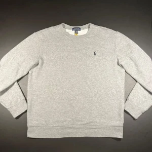 Ralph lauren tröja - Ralph Lauren Sweatshirt i grå med mörkblå logga. Skick 8/10 annvänd men inga hål eller större fläckar på. Storlek XL i barn storlek sitter ungefär som XS i vuxen storlek. Köpt från kidsbrandstore nypris 1095kr. Hör av er vid frågor eller funderingar!