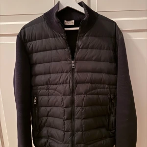 Svart Moncler cardigan - Snygg svart Moncler cardigan. Storlek M. Använd väldigt lite så därför väldigt fräsch. Enda fläcken är under armhålan (mer bilder finns). Köpt här innan på plick för 4500 kr.  För mer bilder eller funderingar är det bara att skriva. Priset ej hugget i sten.