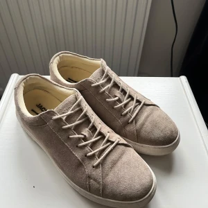 Beige sneakers från Jack & Jones - Snygga beige sneakers från Jack & Jones i mocka med snörning. Perfekta för en avslappnad stil och passar bra till jeans.