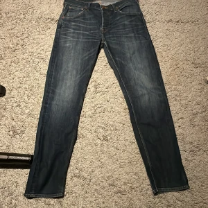 Blå jeansbyxor - Snygga blå jeansbyxor med klassisk femficksdesign och knappgylf. De har en straight passform och är perfekta för en avslappnad stil. Märkeslappen baktill ger en extra touch.