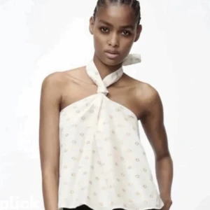 Vit halterneck blus - Snygg vit halterneck blus med små blommönster. Perfekt för sommardagar med sin lätta och luftiga design. Blusen knyts elegant runt halsen och har en lös passform. Kan också tänka mig att byta mot någonting