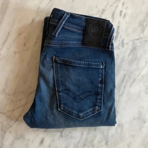 Replay anbass - Snygga blå jeans från Replay med klassisk femficksdesign och knappgylf. Perfekta för en avslappnad stil. Märkesdetaljer på bakfickan och vid linningen ger en extra touch.