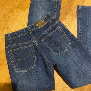 Blå jeans från Only - Snygga blå jeans från Only med klassisk femficksdesign och kontrasterande sömmar. De har en bootcut-stil och knappar i gylfen. Perfekta för en avslappnad look.