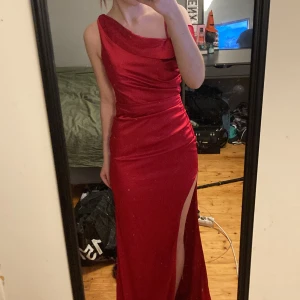 Röd oneshoulder klänning - Elegant röd oneshoulder klänning med en slits och öppen rygg. Perfekt för speciella tillfällen med sin figurnära passform och glänsande material. Använd en gång då under bal, för referens är jag 166💕