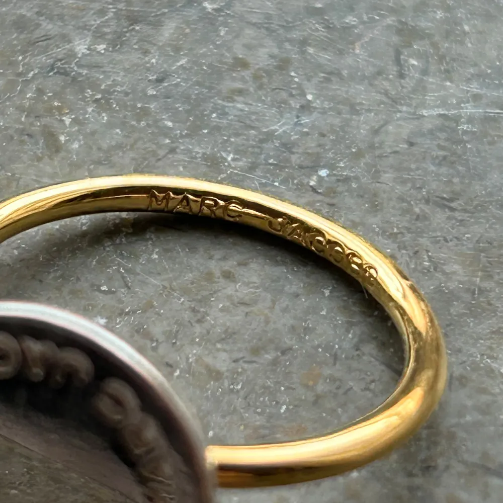 Säljer min marc jacobs ring för att jag ej använder den. Den är äkta och köpt på sellpy. Fint skick!! Plattan uppe på ringen är silver och ringen runt fingret är i guld. Passar perfekt till mina marc jacobs öronhängen jag säljer!!🩷☺️. Accessoarer.