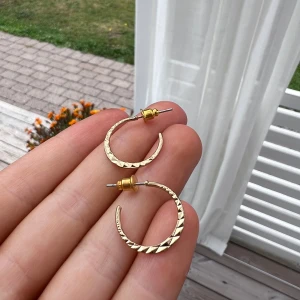 Guldiga örhängen - Guldiga örhängen med textur. Väldigt tunna och eleganta. Sälja pga att de aldrig kom till användning 💞  (ALDRIG ANVÄNDA)  Diameter: 2 cm