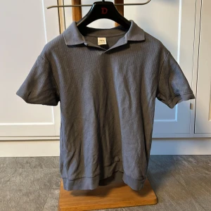 Grå pikétröja från Zara - Säljer en stilren grå pikétröja från Zara i storlek S. Tröjan är kortärmad och har en klassisk krage.