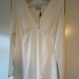 Fin vit klänning  - Fin vit v-ringad klänning i strl 40 från Iva Nikolinas kollektion med NA-KD. Aldrig använd, kan finnas någon jätteliten fläck som går av i tvättmaskinen. 