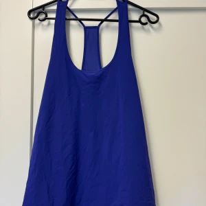 Blå linnetopp från Lululemon - Säljer en snygg blå linnetopp från Lululemon. Perfekt för träning eller en varm sommardag. Toppen är ärmlös och har en stilren design med ett litet Lululemon-märke på sidan. Materialet känns lätt och bekvämt.