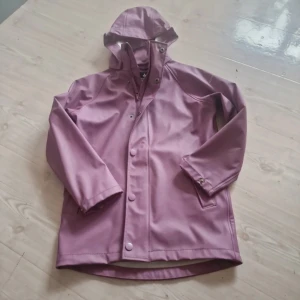 Rosa regnjacka med huva - Säljer en superfin rosa regnjacka med huva. Den har långa ärmar och knappar framtill. Perfekt för regniga dagar och håller dig torr och snygg! 💖