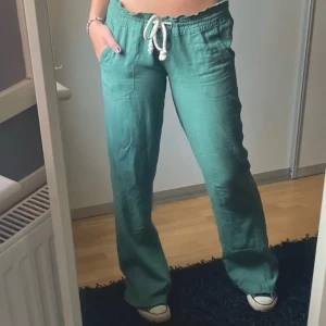 Gröna linnebyxor med snörning - Säljer ett par lågmidjade bootcut gröna linnebyxor med snörning i midjan från Roxy. I bra skick, skriv vid frågor!!