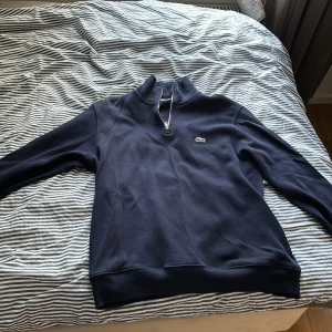 Lacoste zip mörkblå  - Lacoste zip mörkblå mycket bra skick 8/10 bara använd några gånger. Säljer på grund av den inte passar nå mer 