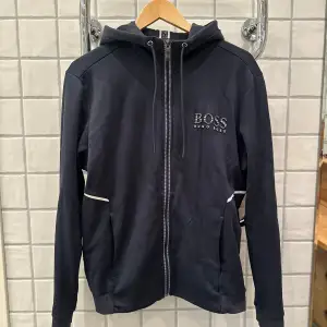 Hugo Boss zipup hoodie i storlek M Skicket är bra förutom på ärmen speciellt på högern (bilder ligger ute med skadorna)  Storlek M och är true to size Skick 7/10