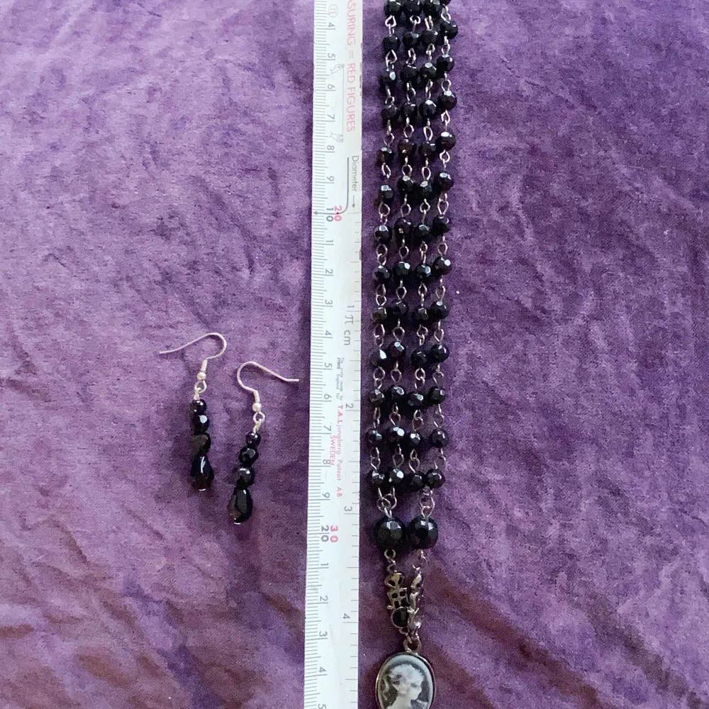 Säljer ett elegant set med ett svart pärlhalsband och matchande örhängen. Halsbandet har ett vackert kamehänge i svart och vitt, vilket ger en klassisk touch. En sten saknas se bild. . Accessoarer.