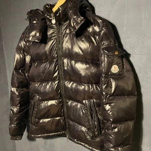 Moncler Maya - Size 2 (M) - 1500 kronor vid snabb affär - jag orkar inte chatta med fler om denna jacka. 🤪. Moncler Maya-jacka säljes. Luva påsydd av skräddare så ingen kan slita av den och stjäla den (sen bild 2).  Kvitto från Plick -  bild 3. 