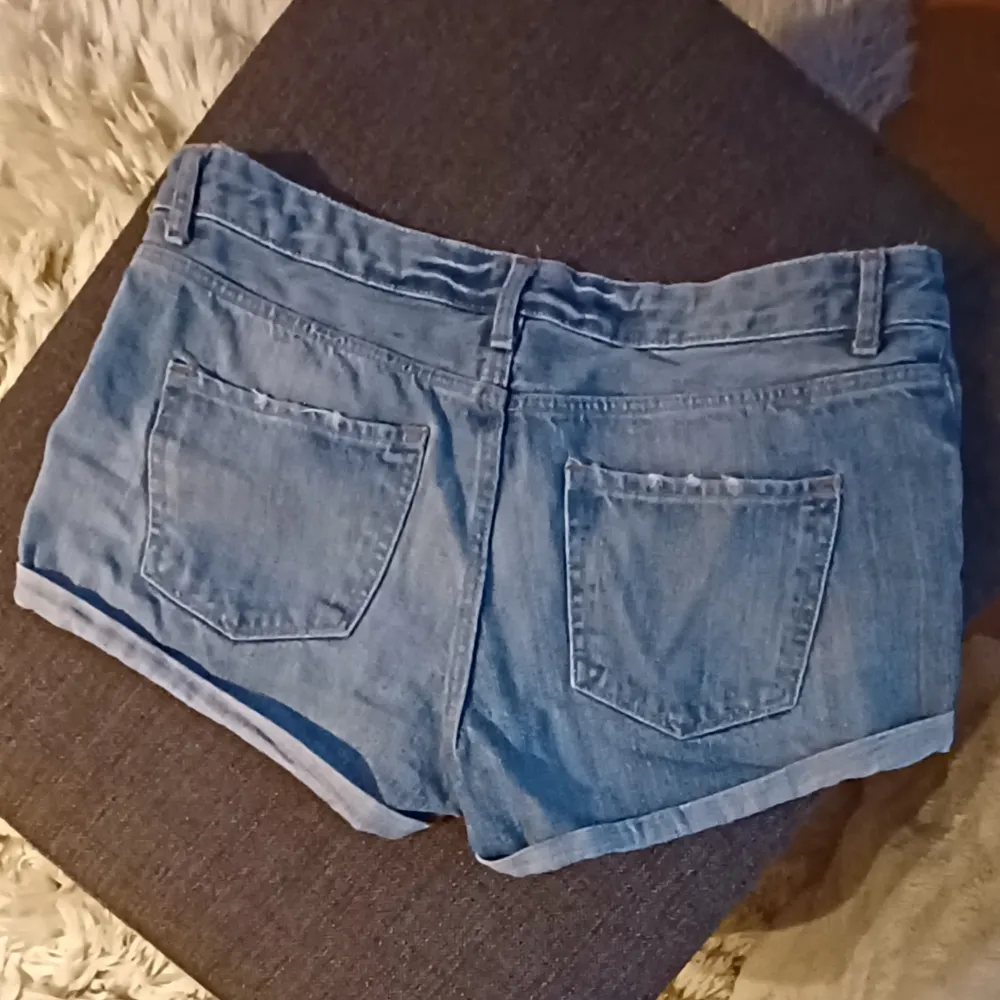 Säljer ett par snygga blå jeansshorts från H&M. De är i nyskick och har en klassisk femficksdesign med knapp och dragkedja fram. Perfekta för sommardagar eller en avslappnad vårlook. Passar till allt från t-shirts till blusar!. Shorts.