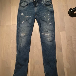 Replay anbass med slitningar - Säljer ett par blå jeans med coola slitningar på framsidan. Replay anbass. Storlek:30/32