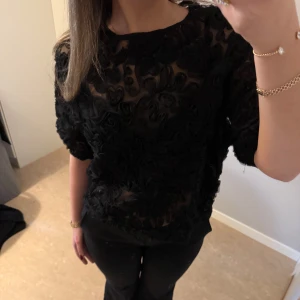Svart blus med blommigt mönster - Använd en gång