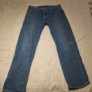 Blå jeansbyxor - Säljer ett par klassiska blå jeansbyxor med en rak passform. De har en traditionell femficksdesign och en knappgylf. Perfekta för en avslappnad stil.