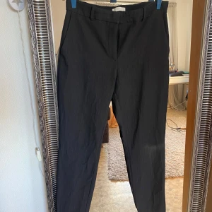 Svarta kostymbyxor - Snygga svarta kostymbyxor med en klassisk passform. Byxorna har en rak stil och är perfekta för en stilren look. De har diskreta fickor baktill och en smidig dragkedja framtill.