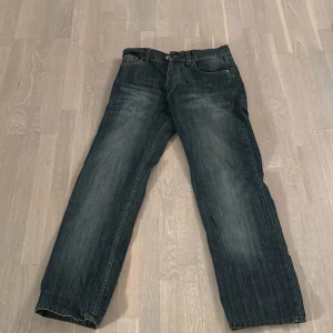 Blå jeansbyxor från Levis - Säljer ett par klassiska blå jeansbyxor från Levis. De har en rak passform och är perfekta för en avslappnad stil. Byxorna har fem fickor och en knappgylf. Perfekta för vardagsbruk!