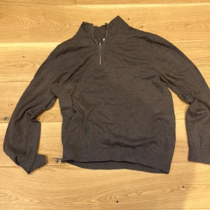 Brun quarterzip  - Säljer en stilren brun tröja med dragkedja vid halsen. Perfekt för kyligare dagar med sin långa ärmar och mjuka material. Passar bra till både jeans och chinos.