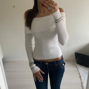 Vit offshoulder topp - Snygg vit offshoulder topp med ribbad design. Den har långa ärmar och en tight passform som framhäver figuren. Perfekt för en stilren look. Den kommer från BikBok💞Det är storlek S på den men skulle mer säga att den passar som en XS/S. Har nog använt den 1 gång, den är i mycket bra skick och den har inte några fläckar eller fel 👍😃