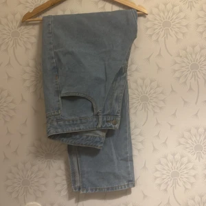Ljusblå jeans med slits - Snygga ljusblå jeans med en liten slits vid benslutet. Perfekta för en avslappnad stil. Klassisk design med fem fickor och knappgylf.