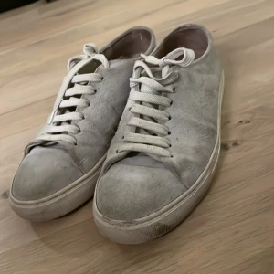 Grå sneakers med snörning - Säljer ett par grå sneakers med snörning. Skorna har en stilren design och är perfekta för vardagsbruk. De är tillverkade i ett material som ger en mjuk känsla och har en klassisk vit sula. Nypris 1499kr