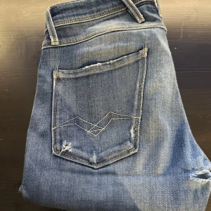 Blå replay jeans med slitningar - Snygga blå replay jeans med slitningar. Ganska bra skick (7/10) det ända problemet jag ser är att det är ett hål vid skrevet. Men detta problem borde gå att lösa väldigt lätt. Men detta därav priset. Hör av dig vid fler funderingar och intresse!