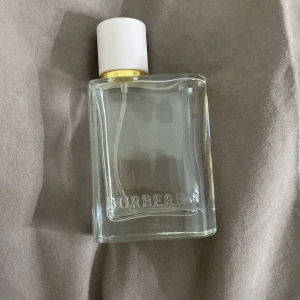 Burberry Eau de Parfum 30 ml - Säljer en elegant Burberry Eau de Parfum i en stilren glasflaska med vit kork och guldiga detaljer. Flaskan rymmer 30 ml och har en klassisk och tidlös design med Burberry-loggan ingraverad. Perfekt för den som älskar lyxiga dofter. Ca 30% kvar.