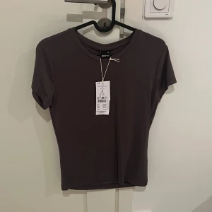 Mörkgrå tshirt GinaTricot - Säljer en mörkgrå t-shirt från Gina Tricot i mjukt material. Har aldrig kommit till användning därför är prislappen kvar… 