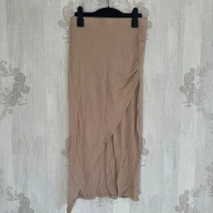 Beige omlottkjol med slits - Snygg beige omlottkjol i ribbat material.  Använd 1-2 gånger, mycket fin
