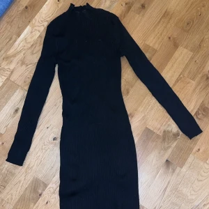 Svart ribbad klänning från H&M - Snygg svart ribbad klänning från H&M i en tight passform. Klänningen har långa ärmar och är knälång för mig som är 175cm. I storlek XS