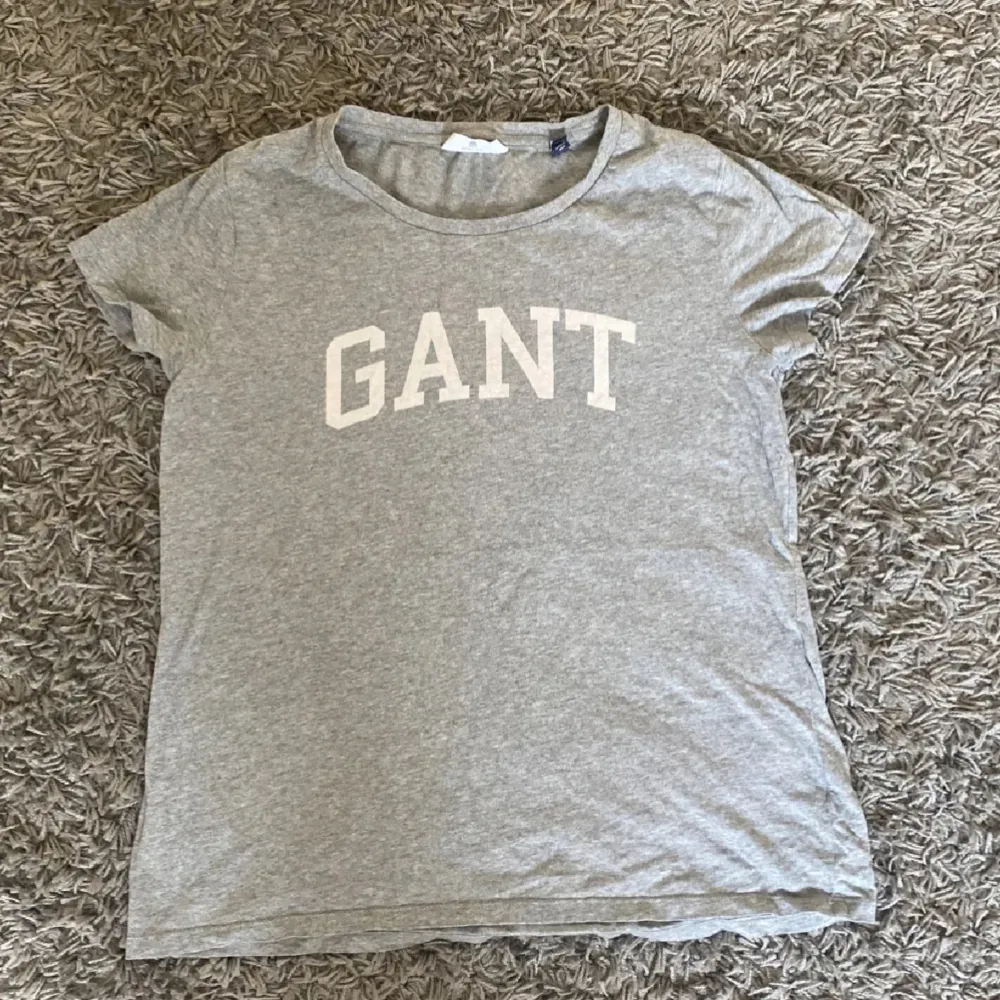 Säljer en grå t-shirt från Gant med vit logga på bröstet. T-shirten har en rund halsringning och korta ärmar. Använd max 5 gånger!💓. T-paidat.