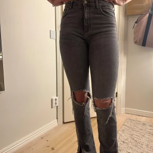 Grå jeans med slitningar - Snygga grå jeans med hög midja och slitningar vid knäna. De har en tight passform.