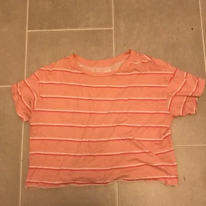Rosa randig t-shirt från Victoria's Secret PINK - Säljer en söt rosa randig t-shirt från Victoria's Secret PINK. Den har korta ärmar och en avslappnad passform. Perfekt för en casual look. 🎀. Lite croppad
