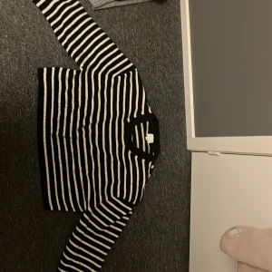 Svart och vit randig tröja - Säljer en snygg svart och vit randig tröja med långa ärmar. Tröjan är stickad och har en klassisk design som passar perfekt för både höst och vinter. Den har en normal passform och är supermjuk och bekväm att bära. Den är lite knottrig vid ärmens slut