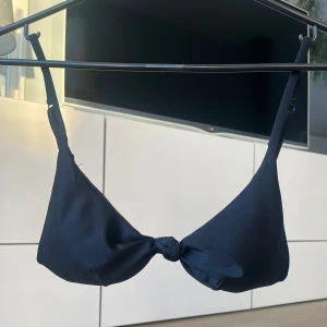 Svart bikiniöverdel - Snygg svart bikiniöverdel i mycket bra skick, med knytning framtill. Justerbara axelband för perfekt passform. Hittar inte storleken med den sitter som S/XS