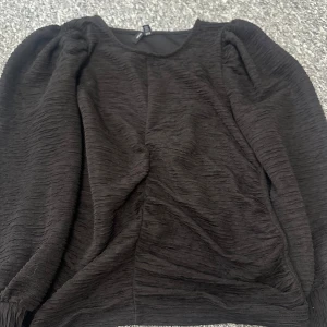 Svart tröja från Vero Moda - Säljer en svart tröja från Vero Moda med en unik textur. Tröjan har långa ärmar och en rund halsringning. Passar snarare M