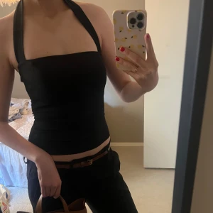 Svart  topp - Snygg svart axelbandslös topp med en stilren design. Perfekt för en trendig look, passar bra till jeans eller kjol. Toppen har en tight passform och är tillverkad i ett mjukt material.