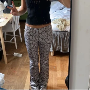 Ormmönstrade byxor - Snygga ormmönstrade byxor med låg midja och bootcut-stil. Perfekta för att sticka ut med sitt unika mönster. Passar bra till både enkla toppar och mer dressade outfits. Jag är 170 lång, köpare står för frakt ❤️