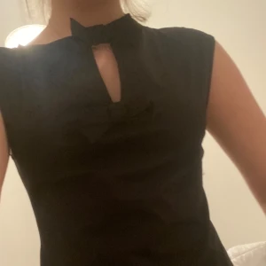 Svart Topp med rosetter från H&M 💗 - Elegant svart topp från H&M med två söta rosetter framtill. Toppen har en stilren design med ärmlös skärning och en liten öppning vid halsen. Perfekt för en elegant look! 🥂Original pris 179,00 kr! Har bara suttit i skåpen aldrig använt🫶🏼