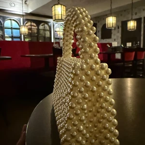 White pearl-adorned handbag - Selling an elegant handbag completely covered in white pearls. The bag has a handle also decorated with pearls, adding a luxurious feel. Perfect for giving your outfit a glamorous touch.