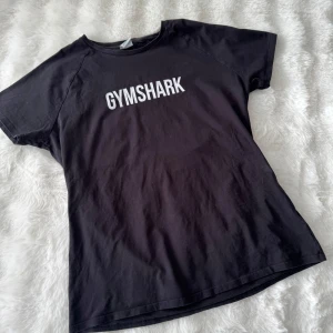 Svart t-shirt från Gymshark - Säljer en svart t-shirt från Gymshark med vit logga på bröstet. Perfekt för träning💕 Storlek xxl men upplevs mer som en xl💕