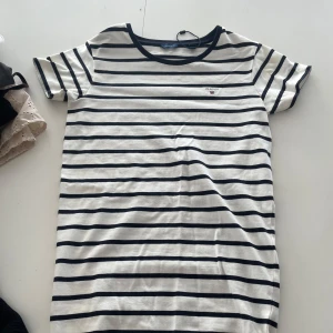 Randig klänning från Gant - Säljer en stilren randig klänning från Gant i marinblått och vitt. Klänningen har korta ärmar och ett broderat Gant märke på bröstet. Perfekt för en avslappnad och snygg look. Går ner till mitten på låret ungefär!! Använd fåtal gånger skriv för fler bilder eller mått💓💓