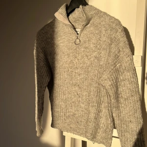 Grå stickad tröja från ONLY - Säljer en mysig grå stickad tröja från ONLY med dragkedja och hög krage. Perfekt för kyliga dagar. Tröjan har långa ärmar och en avslappnad passform. Passar bra till både jeans och kjol.