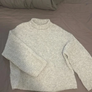 Ljus grå stickad tröja från Gina Tricot - Mysig grå stickad tröja från Gina Tricot. Perfekt för kyliga dagar med sin höga krage och långa ärmar. Knappt använd 💕